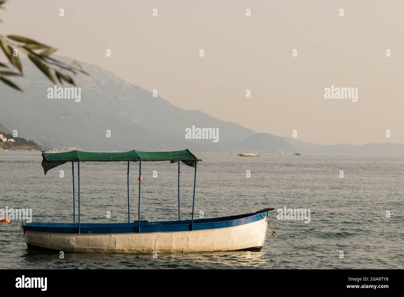Barca con un tetto sul lago Ohrid con le montagne in lontananza Foto Stock