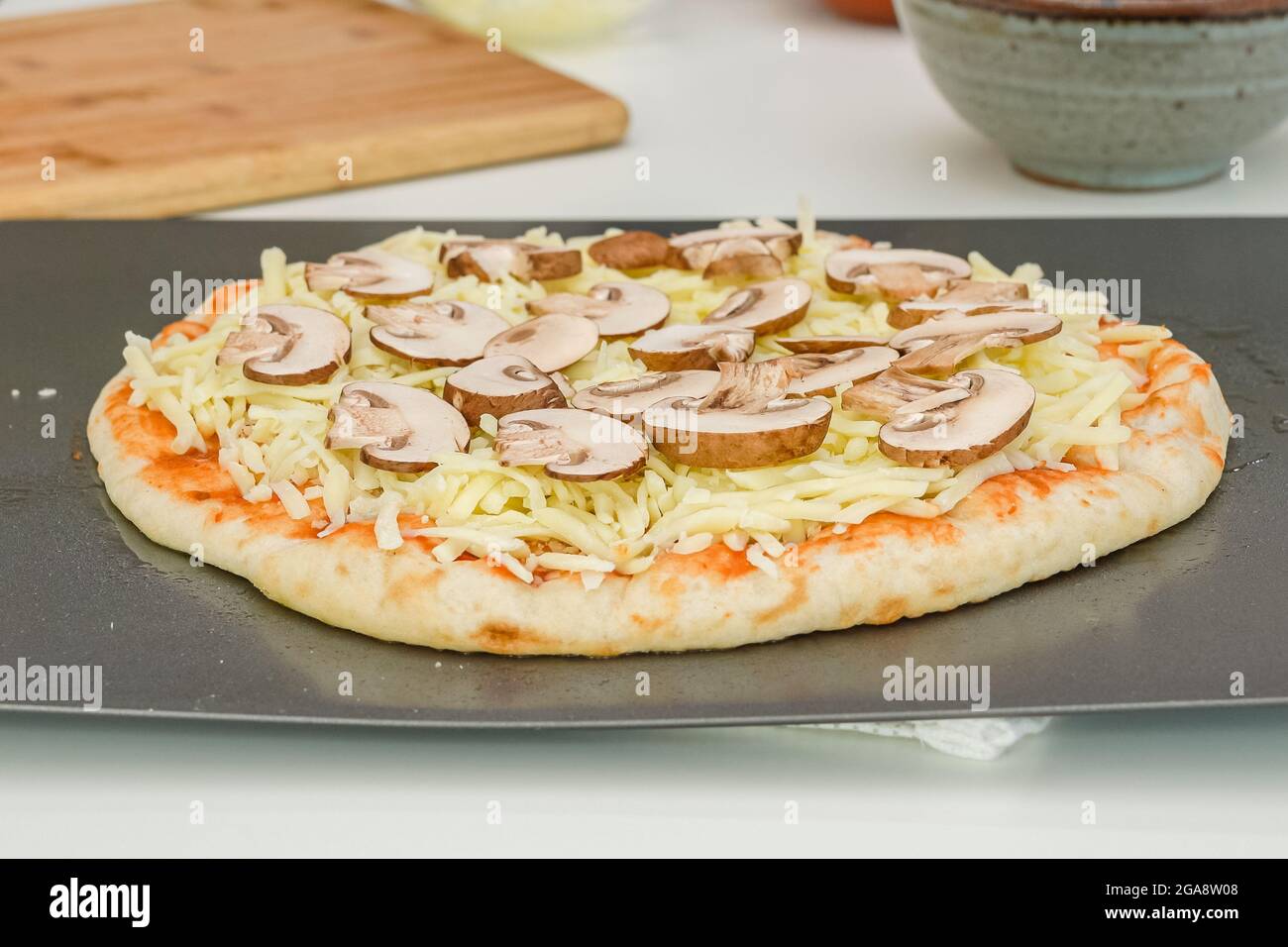 Pasta cruda per pizza con salsa di pomodoro, mozzarella e fette di funghi cremini. Processo di cottura passo dopo passo, ricetta Foto Stock