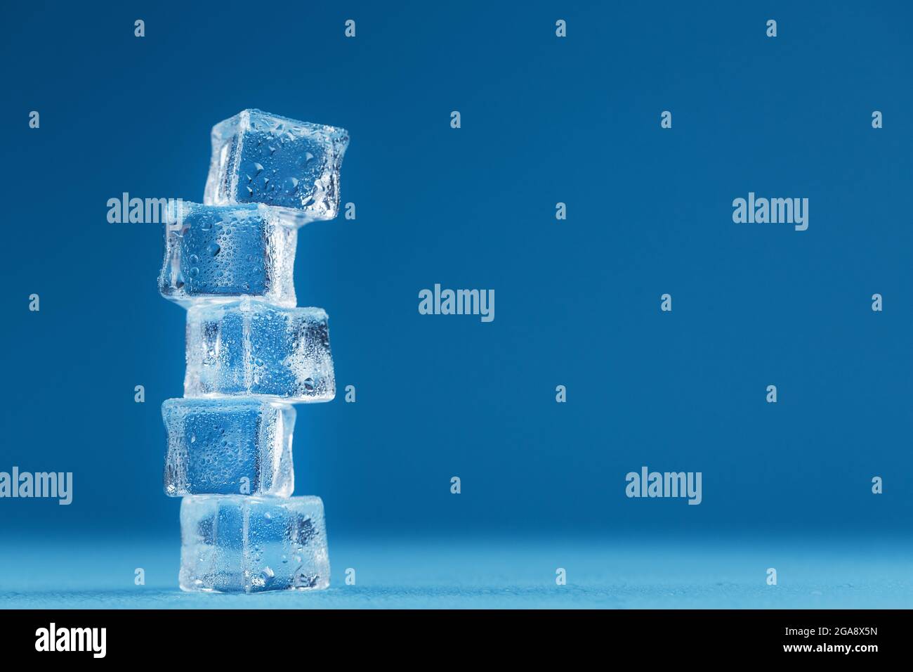 Cubetti di torre di ghiaccio fondente su sfondo blu. Spazio libero Foto Stock