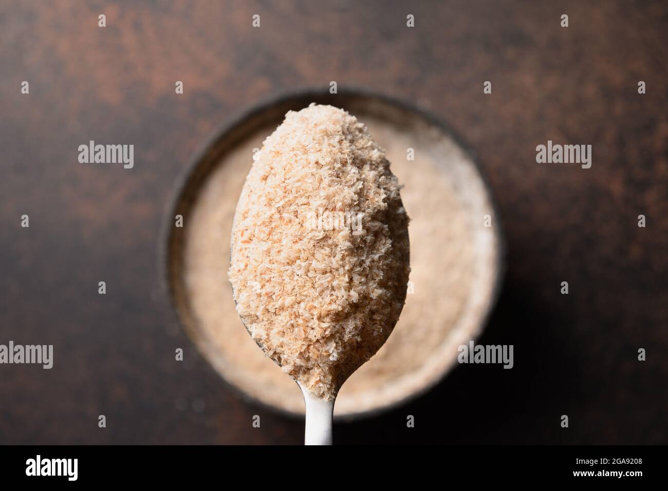 Psyllium buccia in cucchiaio su sfondo marrone. Isabgol. Vista dall'alto. Primo piano. Foto Stock