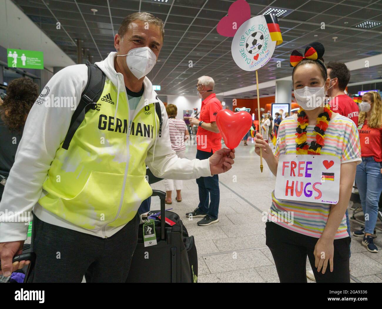 29 luglio 2021, Hessen, Francoforte sul meno: Stefan Kuntz (l), allenatore della squadra di calcio maschile tedesca U21, riceve una mongolfiera a forma di cuore dal tifoso Lisa Lyashkevich (r) dopo il suo ritorno dalle Olimpiadi di Tokyo. Foto: Frank Rumpenhorst/dpa Foto Stock