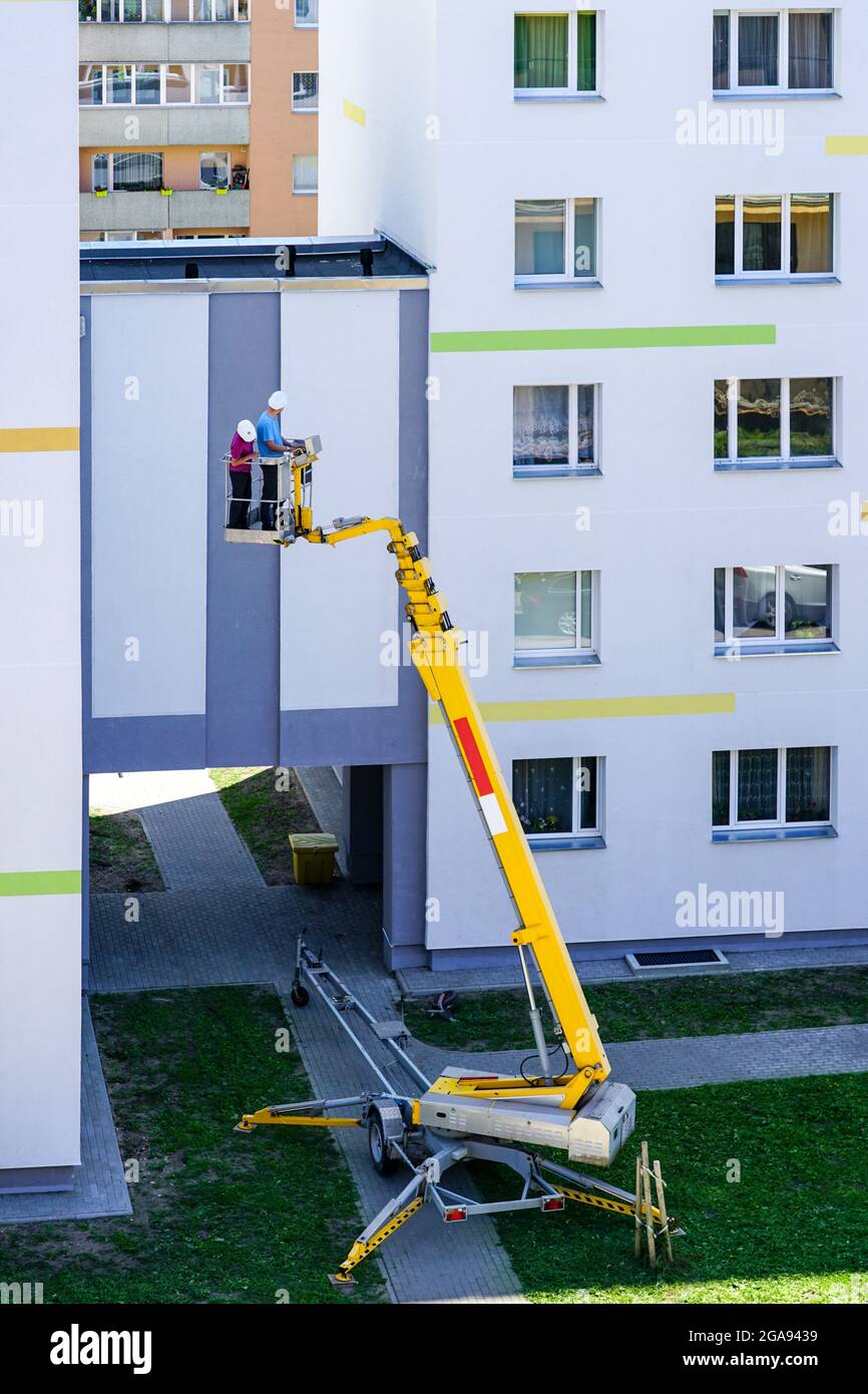 lo specialista ispeziona la facciata della casa con l'aiuto di una moderna piattaforma di sollevamento idraulico semovente mobile Foto Stock