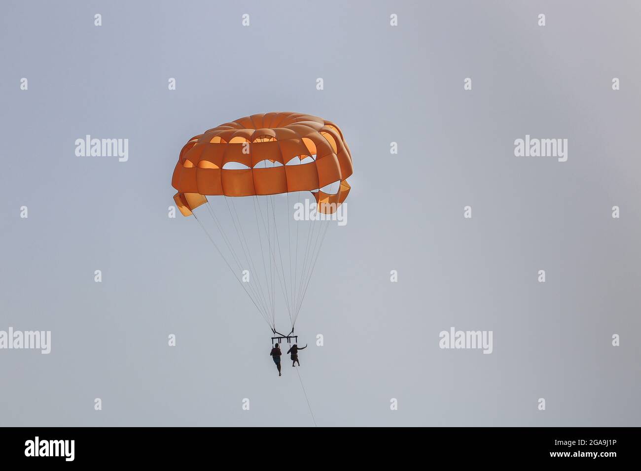 Orange Paracadute High in the Sky con due persone sul parasailing Foto Stock