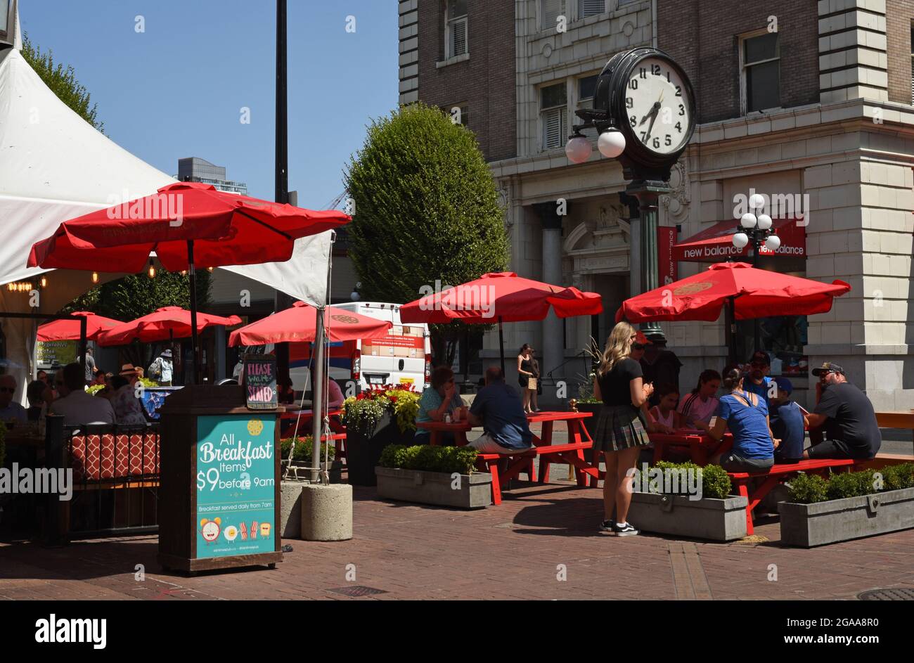 Il patio esterno di un ristorante è protetto dal sole da ombrelloni rossi su Government Street a Victoria, British Columbia, sull'isola di Vancouver. Foto Stock