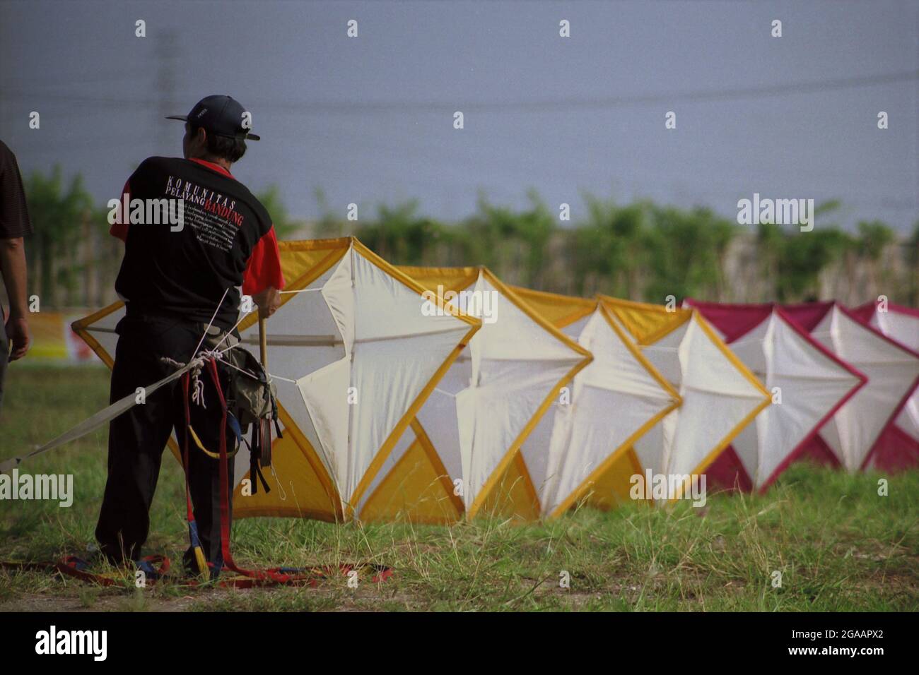 Un uomo che prepara un aquilone gigante durante il Festival Internazionale del Kite di Giacarta del 2004 che si è tenuto il 9-11 luglio a Carnival Beach ad Ancol Dreamland, Jakarta Nord, Giacarta, Indonesia. Foto Stock