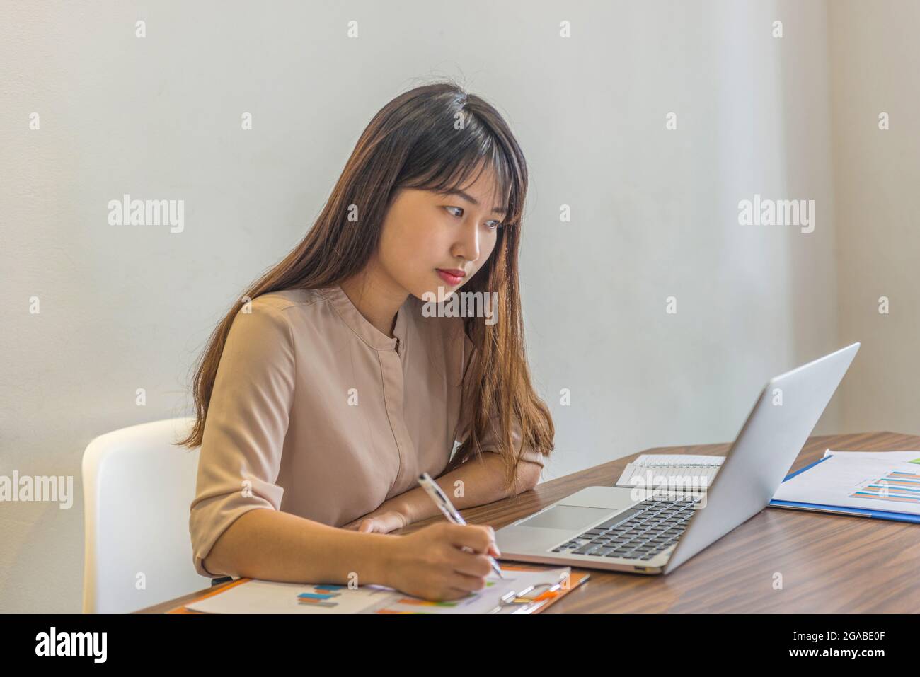 Giovane freelance che scrive appunti e lavora su un computer portatile a casa Foto Stock