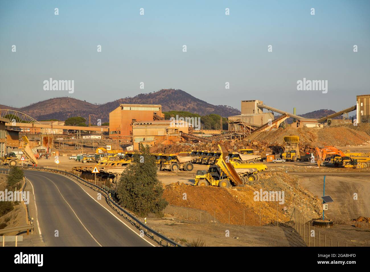 Zone circostanti delle miniere di Aracena, dove si può vedere una strada circondata da macchinari, piante e una miniera Foto Stock