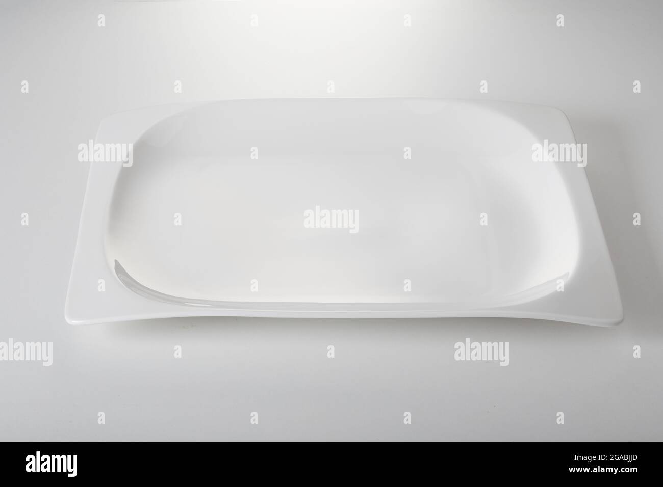 Dall'alto di una nuova piastra rettangolare vuota posta su sfondo bianco in cucina Foto Stock