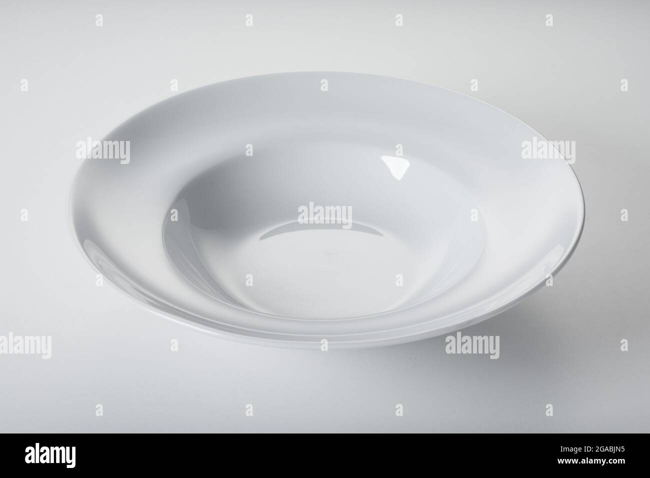 Dall'alto della ciotola in ceramica pulita e lucida posta su sfondo bianco in cucina Foto Stock