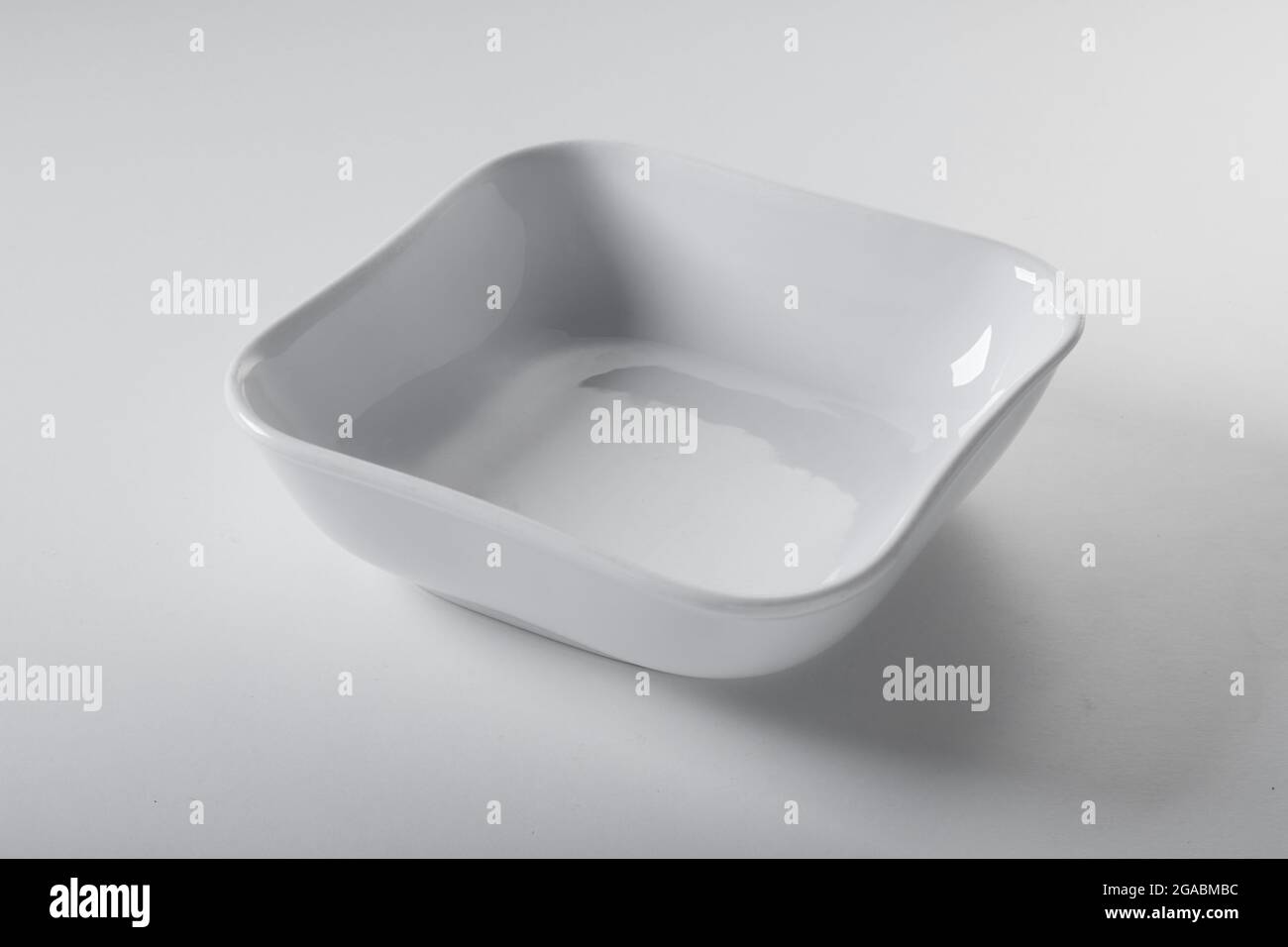 Alto angolo di ceramica pulita a forma quadrata recipiente servito su sfondo bianco in cucina Foto Stock