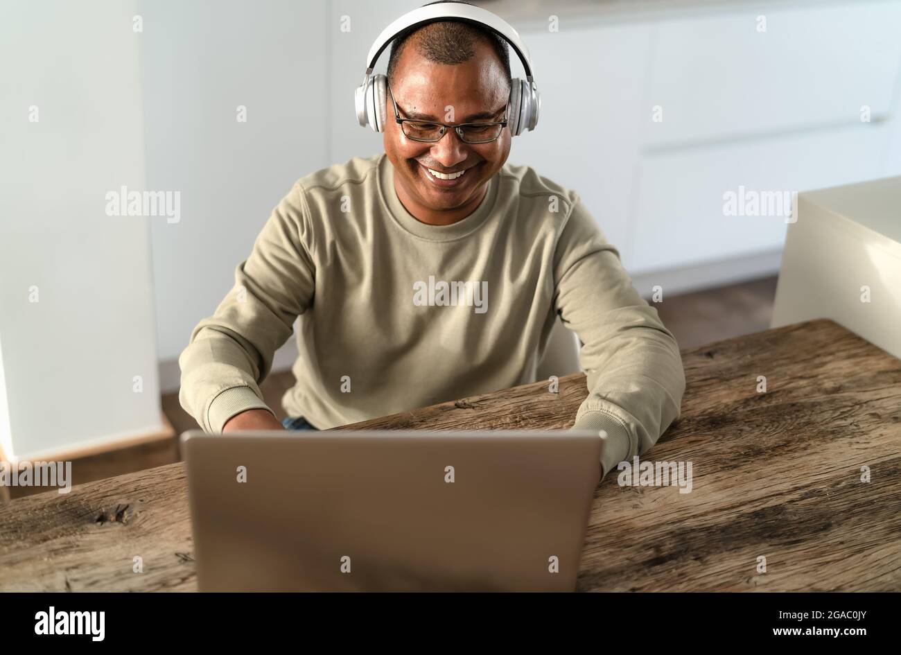 Felice uomo anziano che lavora in modo intelligente utilizzando il laptop a casa - concetto di tecnologia Foto Stock