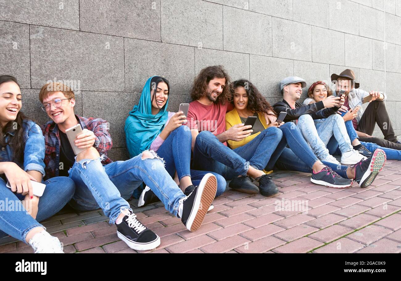 Giovane gruppo multirazziale di amici che usano lo smartphone mobile outdoor - concetto di stile di vita giovanile millenario Foto Stock
