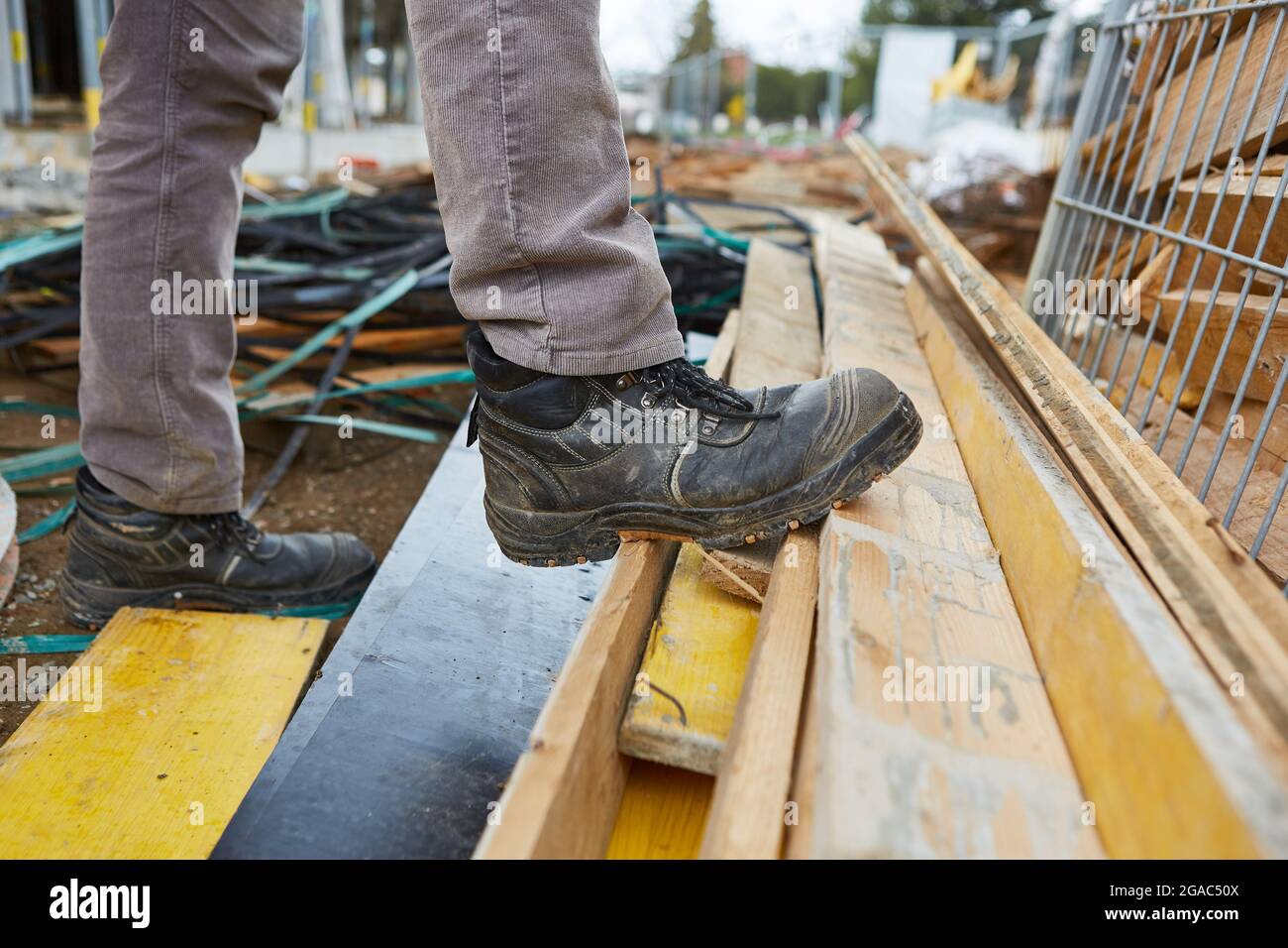 Scarpe di sicurezza di lavoratori o artigiani in un cantiere con rifiuti di legno e macerie Foto Stock