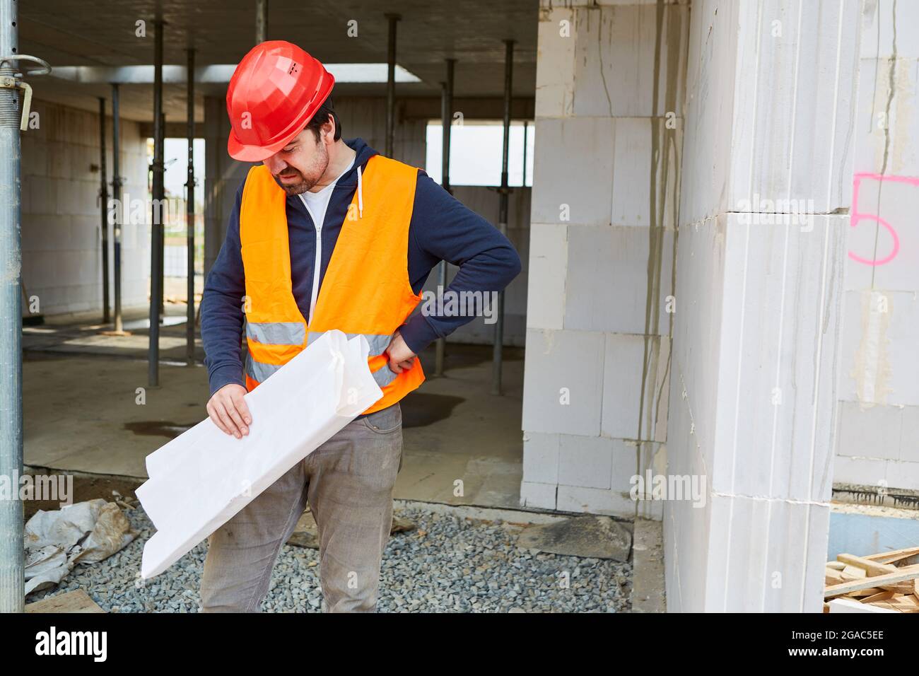 Il caposquadra con il blueprint pensa ad un problema con la progettazione sul luogo di costruzione nella conchiglia Foto Stock