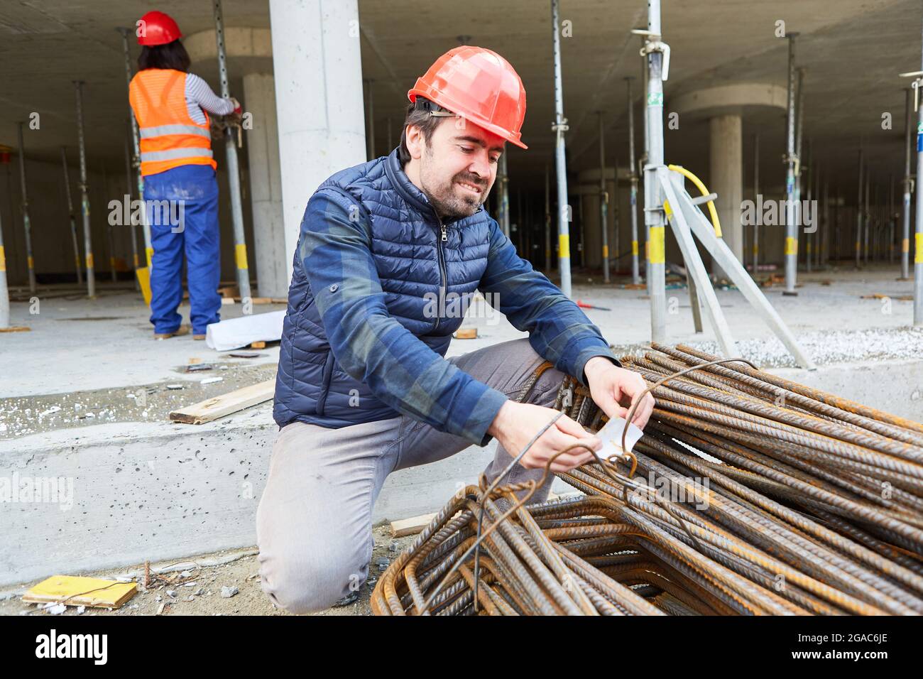 Lavoratori edili durante il controllo di qualità della fornitura di acciaio di rinforzo sul guscio di un cantiere Foto Stock