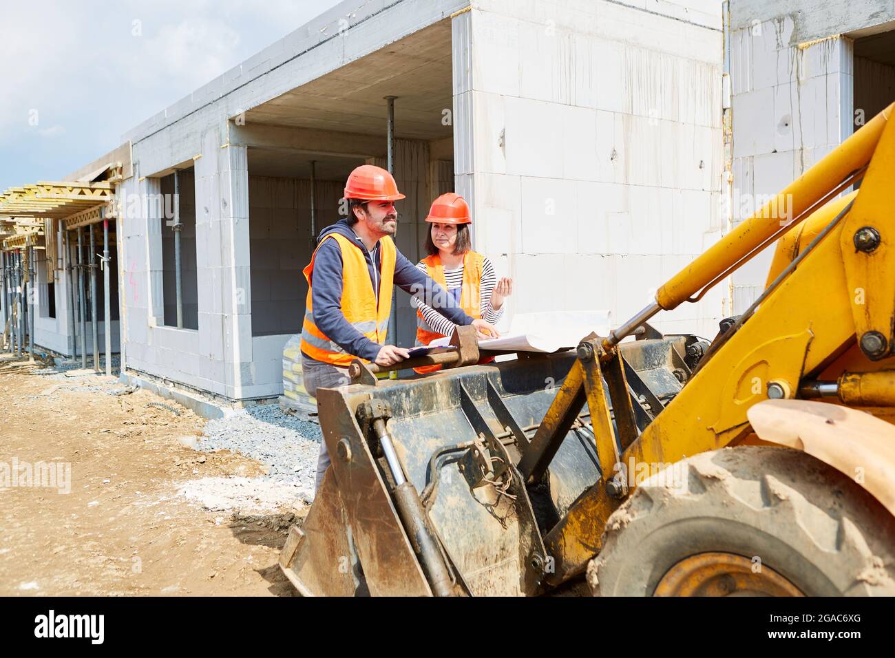 L'architetto e il caposquadra discutono del progetto di costruzione sul cantiere per la costruzione di uffici o abitazioni Foto Stock