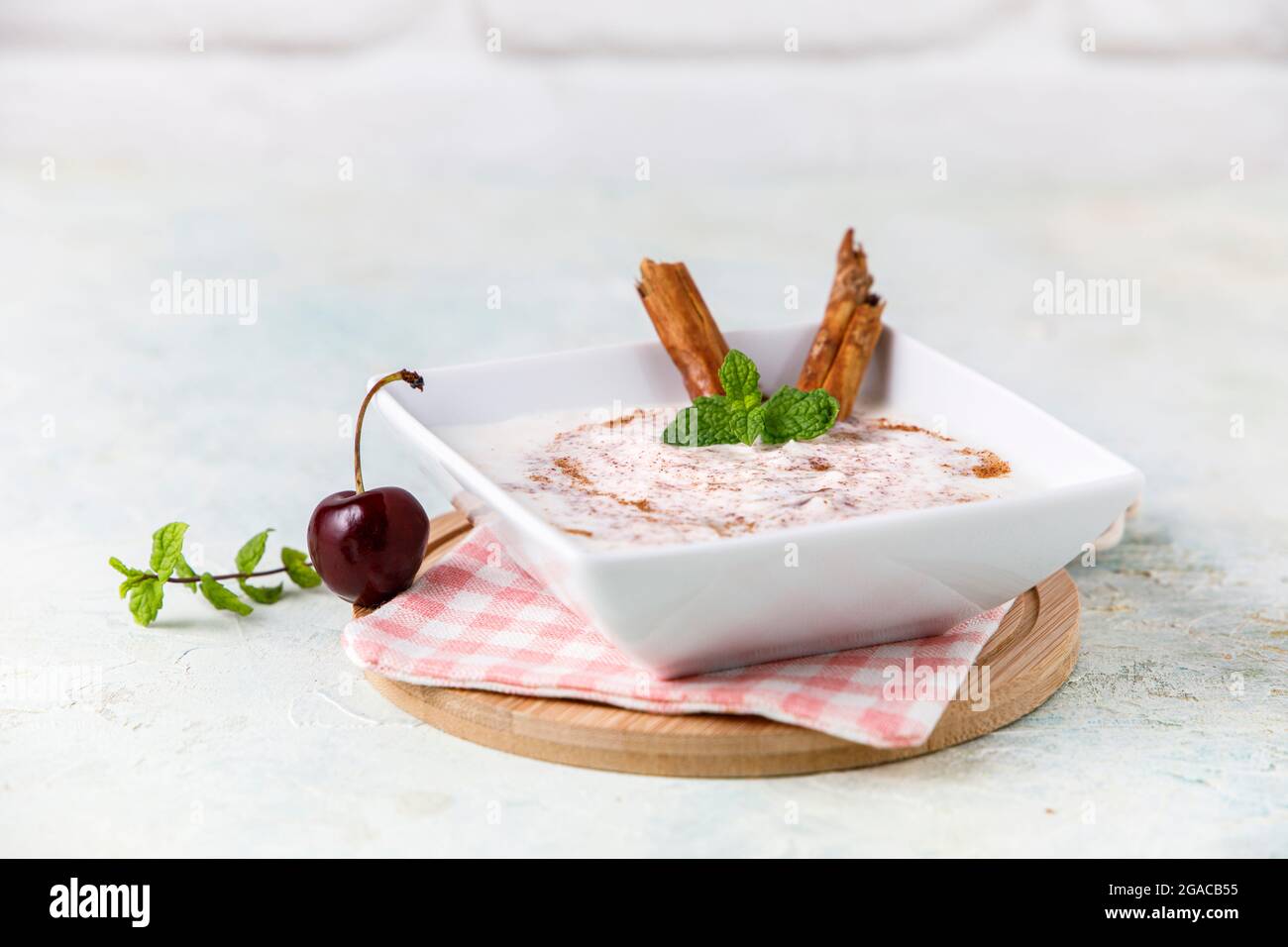 Budino di riso fatto in casa con cannella e ciliegie in una ciotola bianca su legno Foto Stock