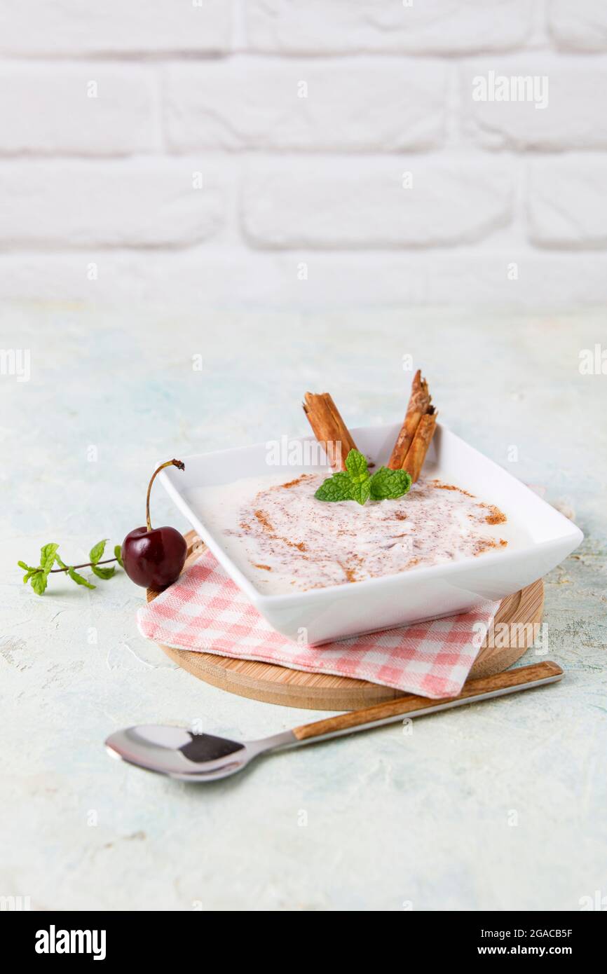 Budino di riso fatto in casa con cannella e ciliegie in una ciotola bianca su legno Foto Stock