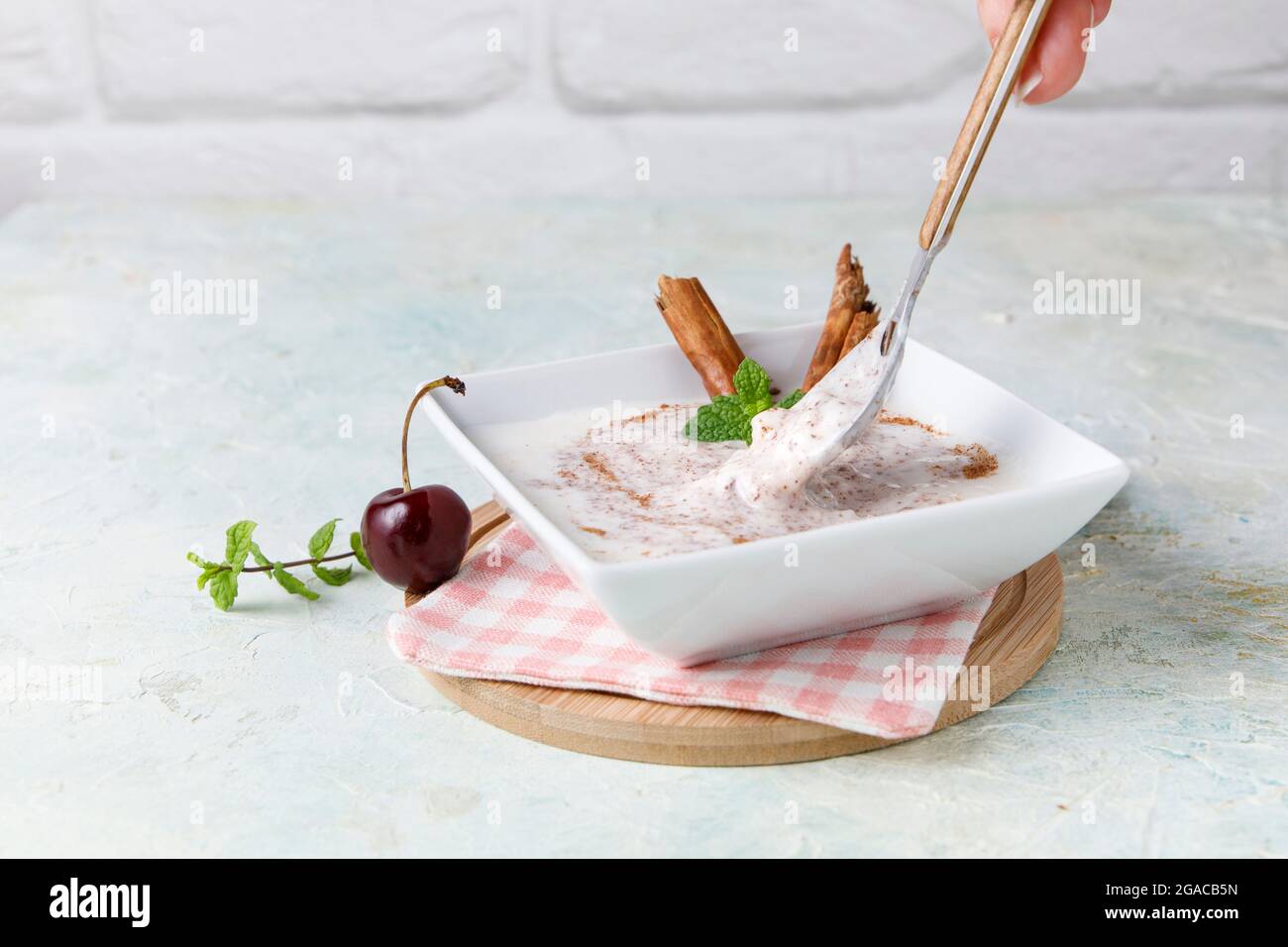 Budino di riso fatto in casa con cannella e ciliegie in una ciotola bianca su legno Foto Stock