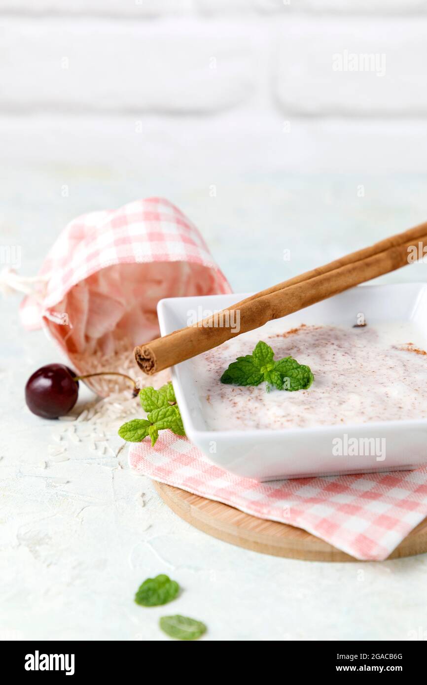 Budino di riso fatto in casa con cannella e ciliegie in una ciotola bianca su legno Foto Stock