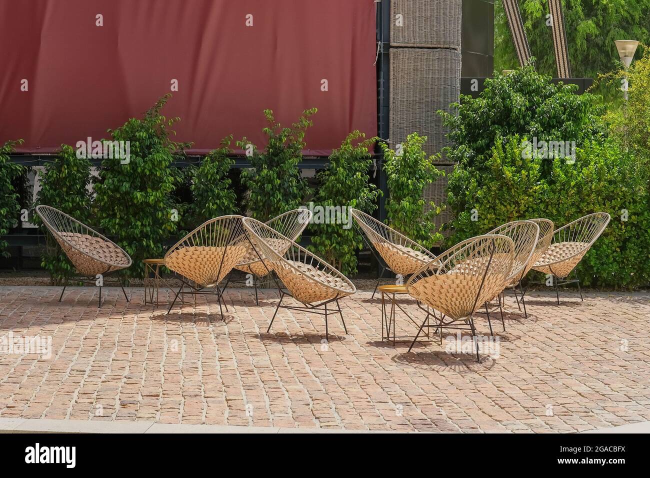 Terrazza con comodi mobili in vimini moderni. Moderne sedie in vimini crema fatte a mano in rattan naturale in un cafe vuoto. Foto Stock