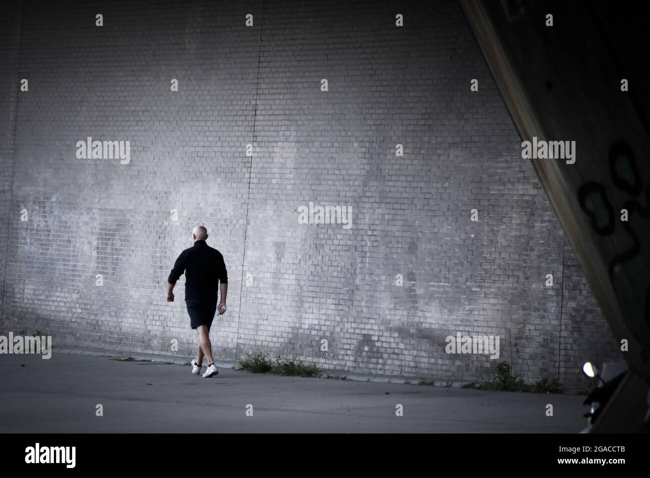 Vista posteriore di un uomo che cammina vicino a un muro. Foto Stock