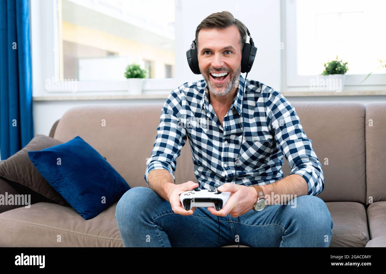 Uomo che gioca ai giochi per computer, che gioca alla console, che tiene le pedine nelle mani Foto Stock