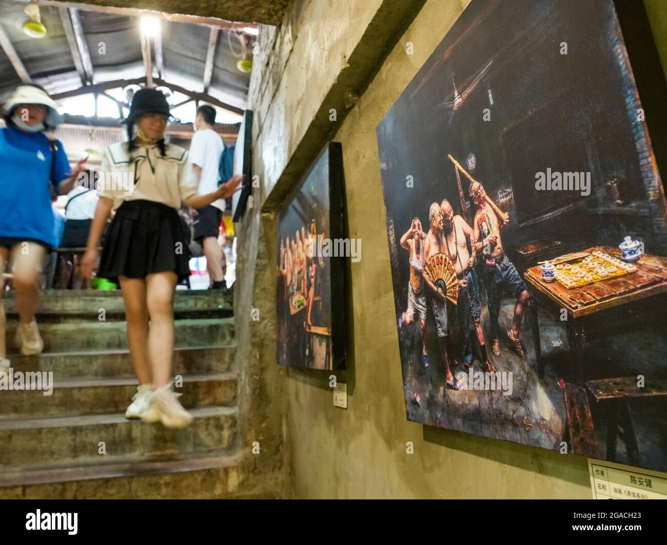 (210730) -- CHONGQING, 30 luglio 2021 (Xinhua) -- i turisti visualizzano le opere d'arte di Chen Anjian al Teahhouse delle Comunicazioni nel Chongqing del sud-ovest della Cina, 26 luglio 2021. Chen Anjian, 62 anni, insegnante di pittura ad olio presso il Sichuan fine Arts Institute, frequenta la Chongqing Communications Teahhouse per più di 20 anni. Fondata nel 1987, la sala da tè Communications è ora l'unica vecchia casa da tè di Chongqing che ha mantenuto lo stile originale degli anni '70 e '80. E' uno dei punti di riferimento culturali chiave di Chongqing, e visitato ogni giorno da migliaia di amanti del tè. "La Teahhouse delle Comunicazioni Foto Stock
