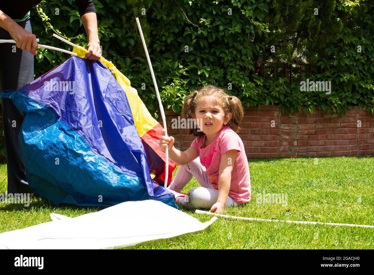 La ragazza e la madre stanno cercando di installare la tenda di gioco nel loro giardino. Foto Stock