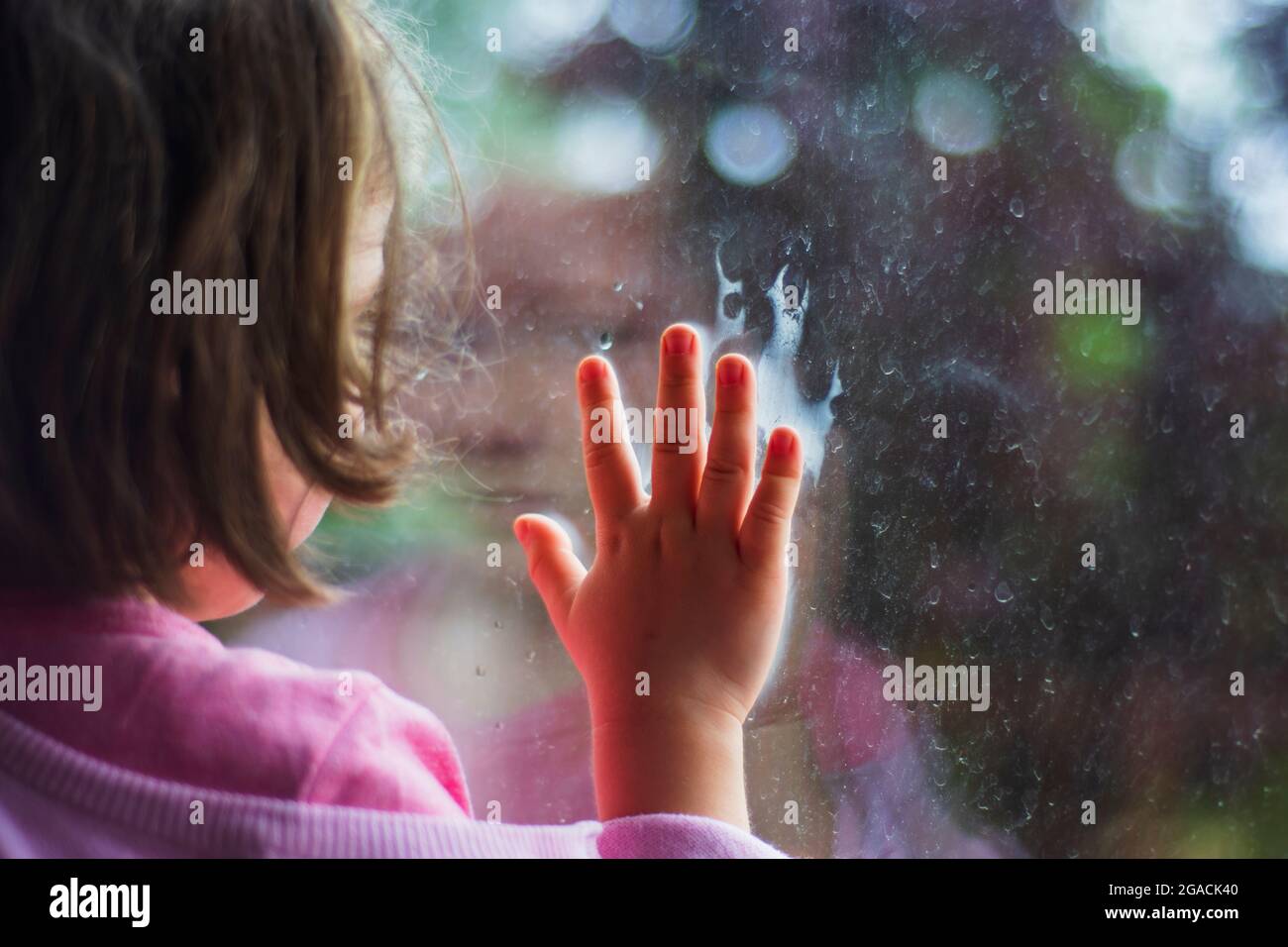 bambina che guarda fuori la finestra della sua casa. Fuoco selettivo ragazza. Foto Stock