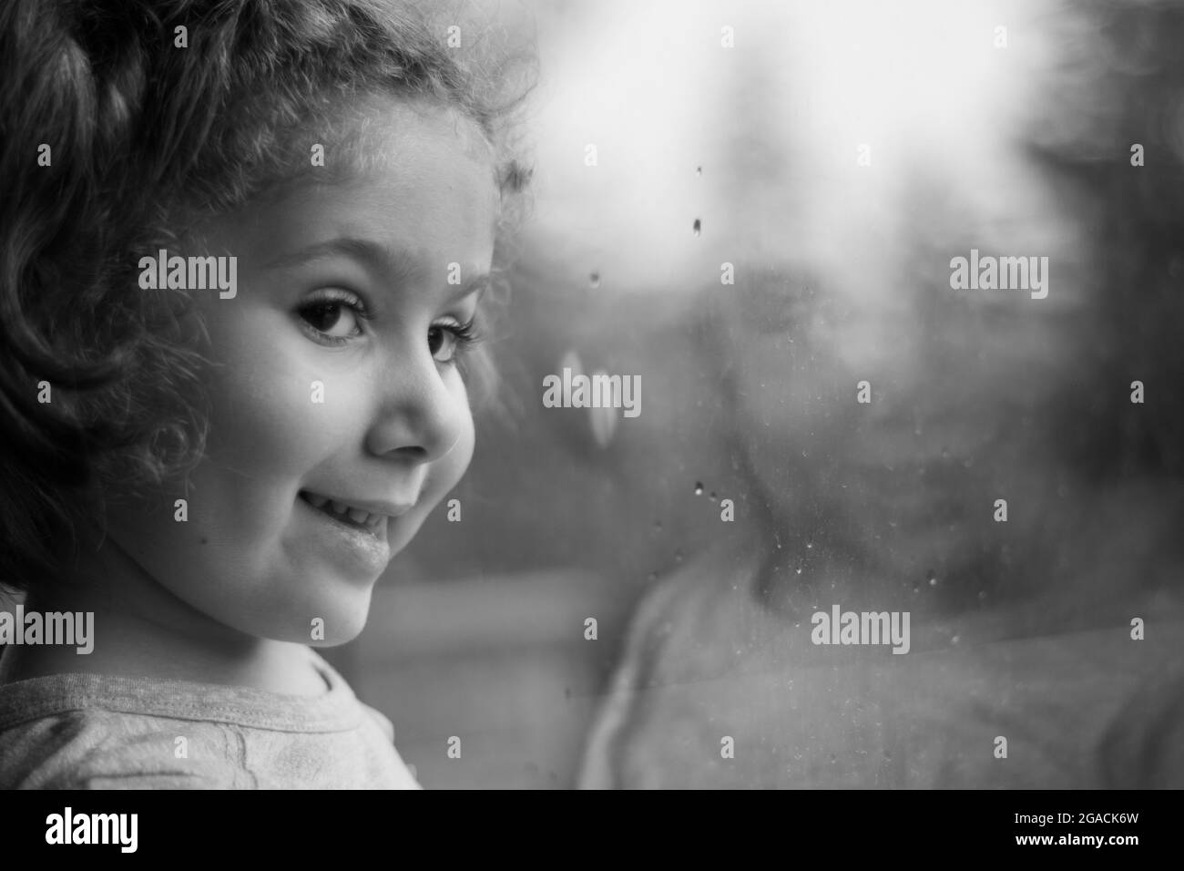 bambina che guarda fuori la finestra della sua casa. Fuoco selettivo ragazza. Foto Stock