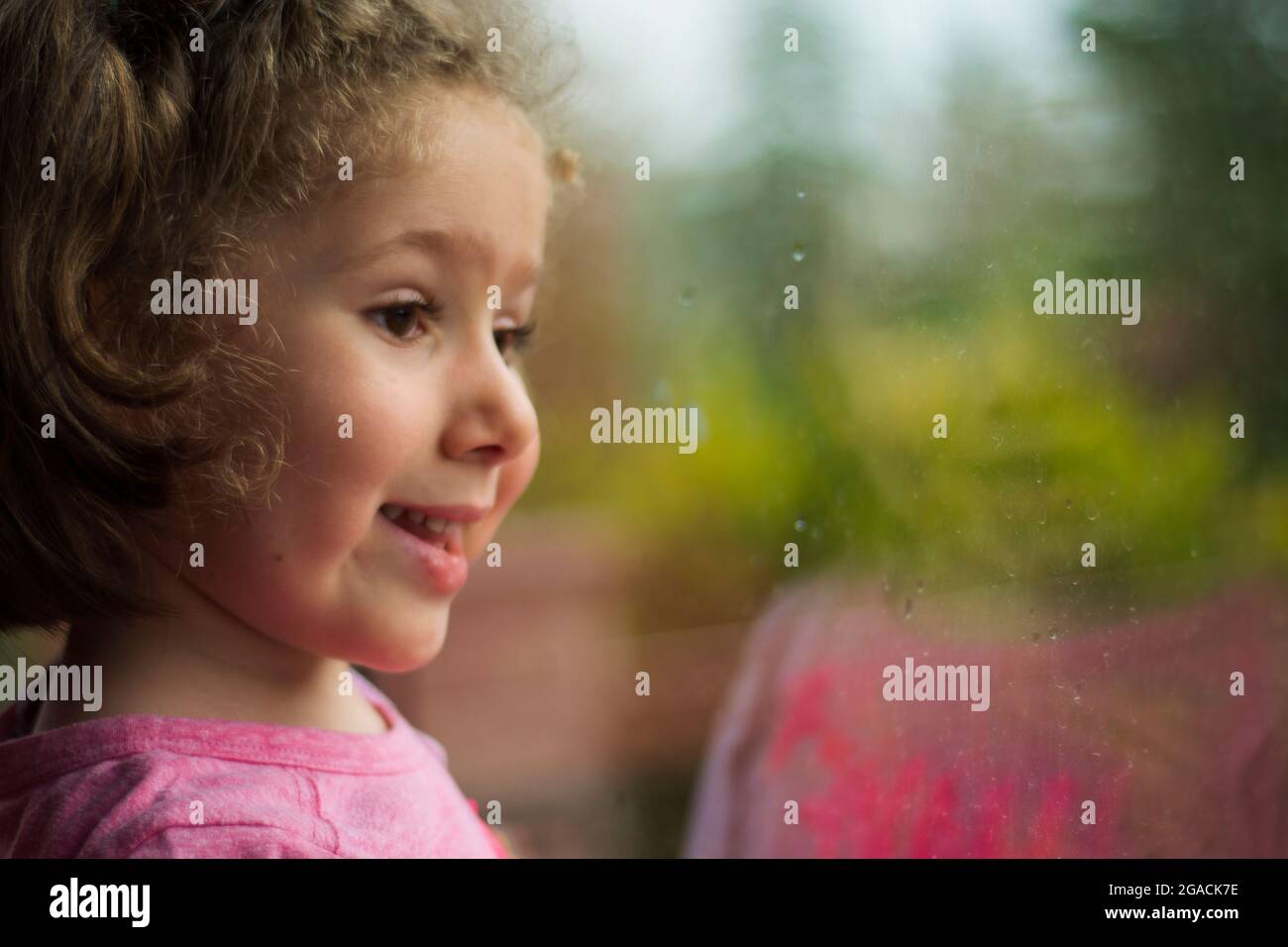 bambina che guarda fuori la finestra della sua casa. Fuoco selettivo ragazza. Foto Stock