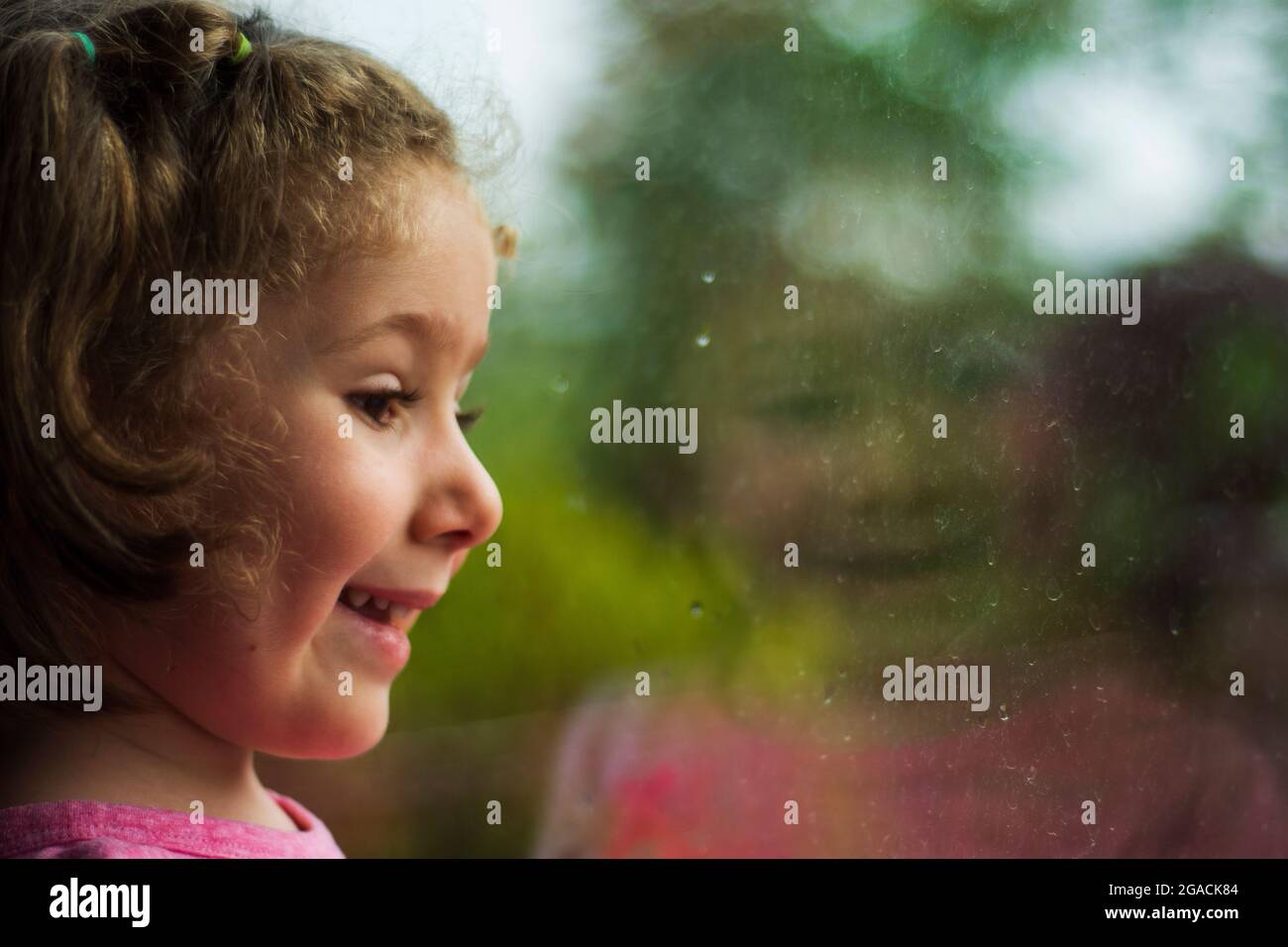bambina che guarda fuori la finestra della sua casa. Fuoco selettivo ragazza. Foto Stock