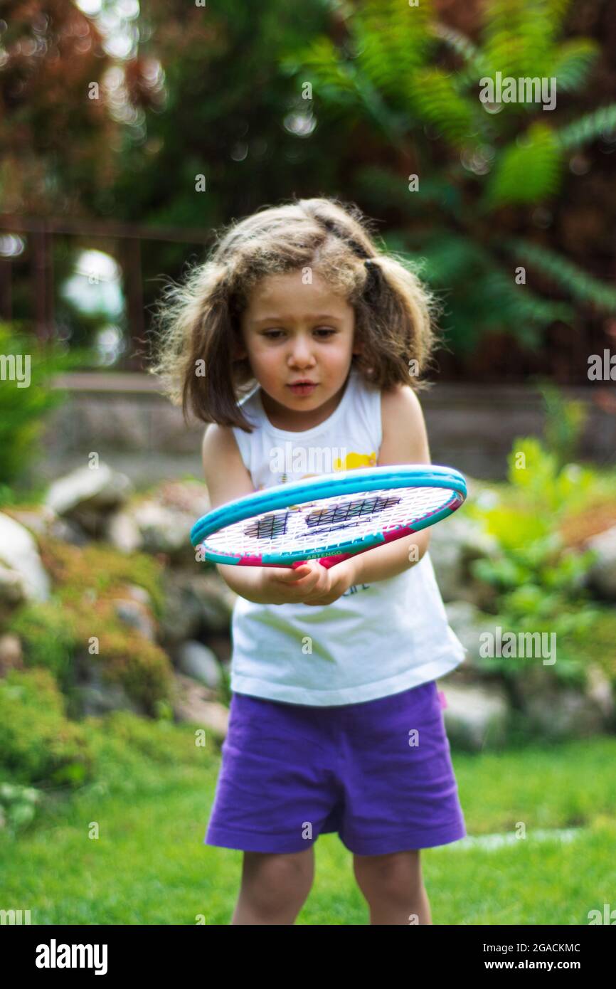 Bambina che gioca a tennis nel suo giardino in una giornata estiva. Focus Girl selettivo Foto Stock