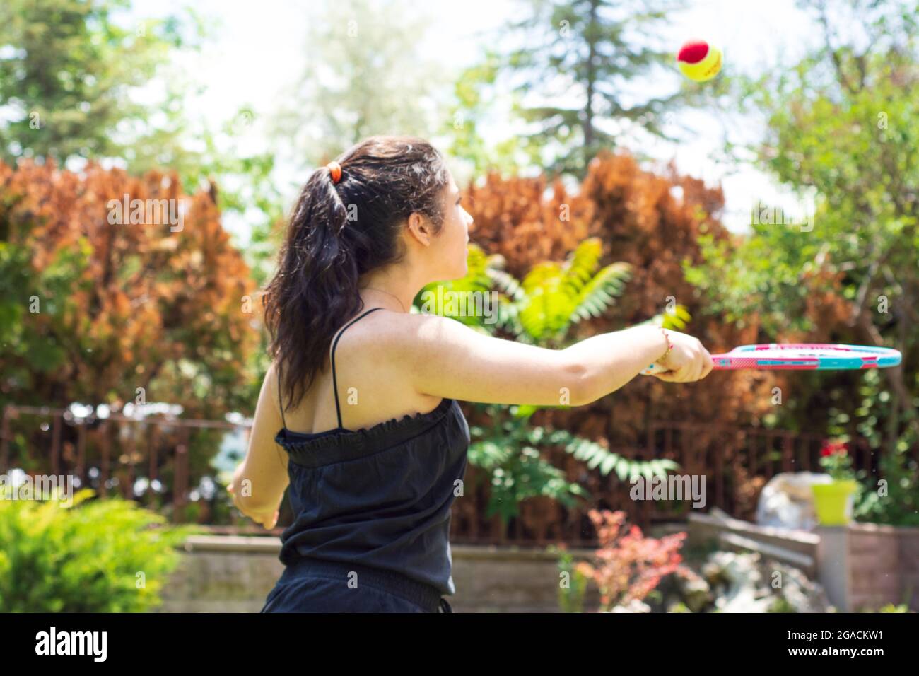 Bambina che gioca a tennis nel suo giardino in una giornata estiva. Focus Girl selettivo Foto Stock