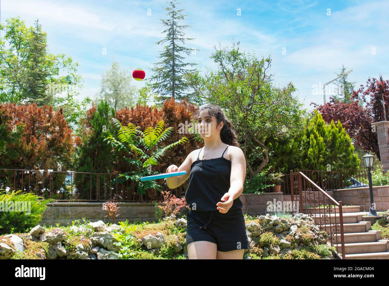 Bambina che gioca a tennis nel suo giardino in una giornata estiva. Focus Girl selettivo Foto Stock