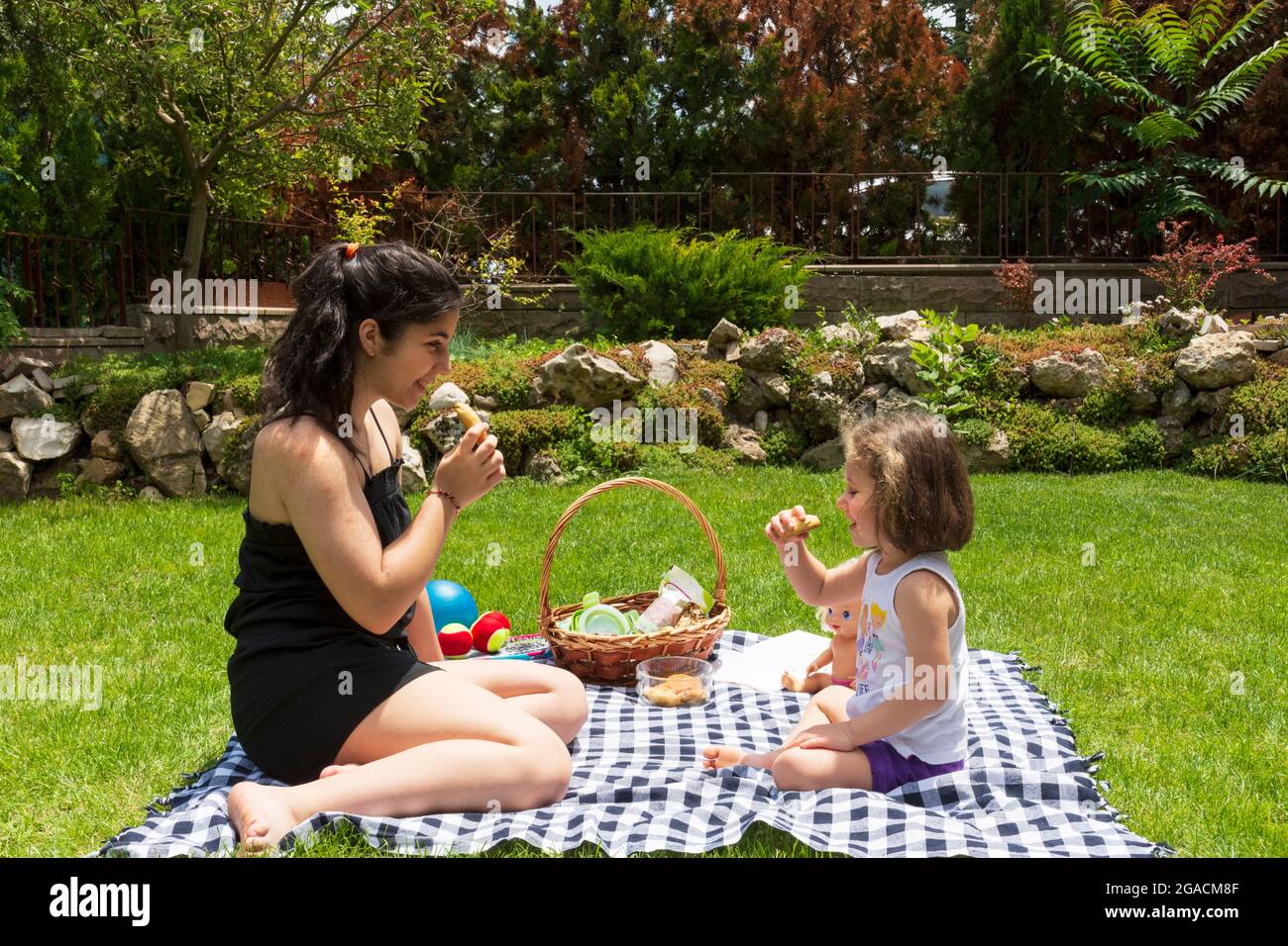 la bambina e la sorella stanno giocando a giochi e facendo un picnic in giardino Foto Stock