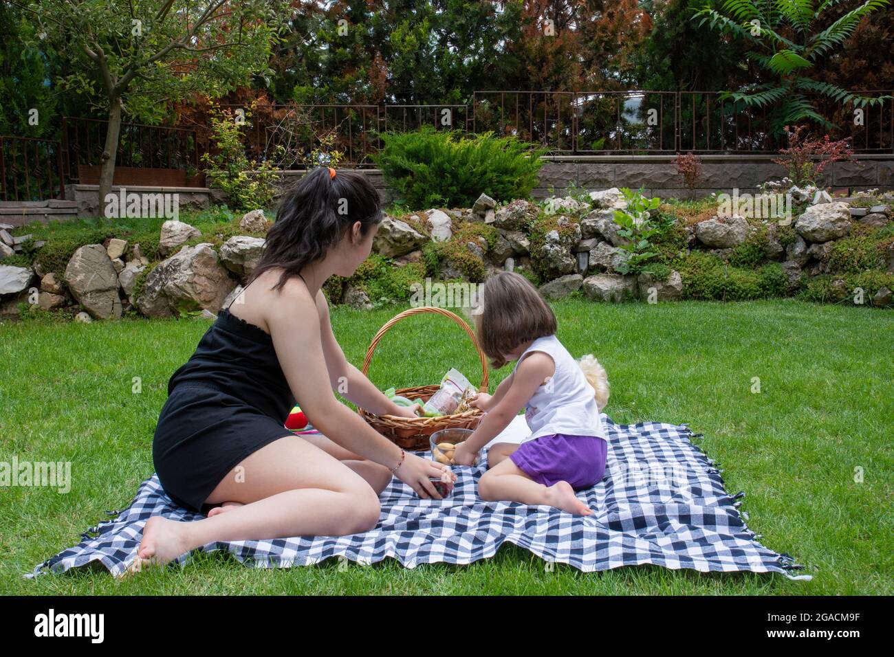 la bambina e la sorella stanno giocando a giochi e facendo un picnic in giardino Foto Stock