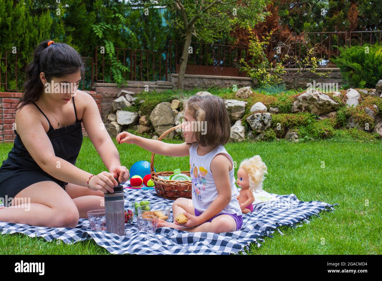 la bambina e la sorella stanno giocando a giochi e facendo un picnic in giardino Foto Stock