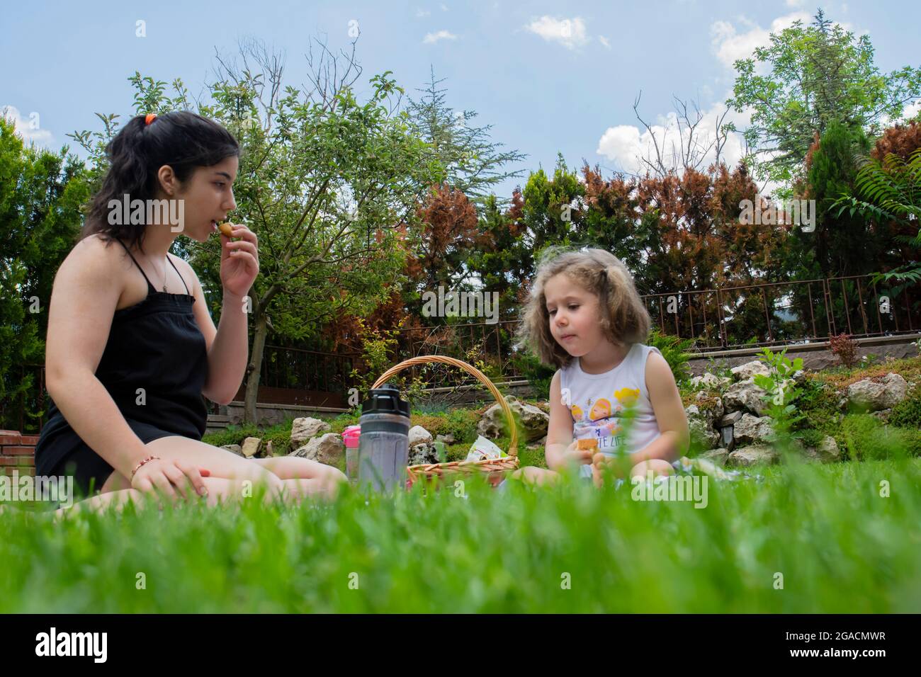 la bambina e la sorella stanno giocando a giochi e facendo un picnic in giardino Foto Stock