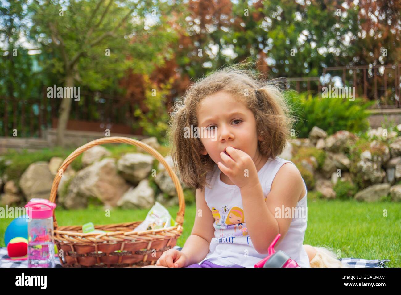 Bambina che ha un picnic nel loro giardino in una calda giornata estiva Foto Stock