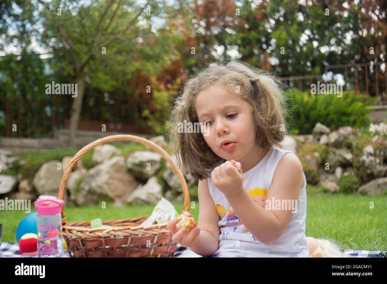 Bambina che ha un picnic nel loro giardino in una calda giornata estiva Foto Stock