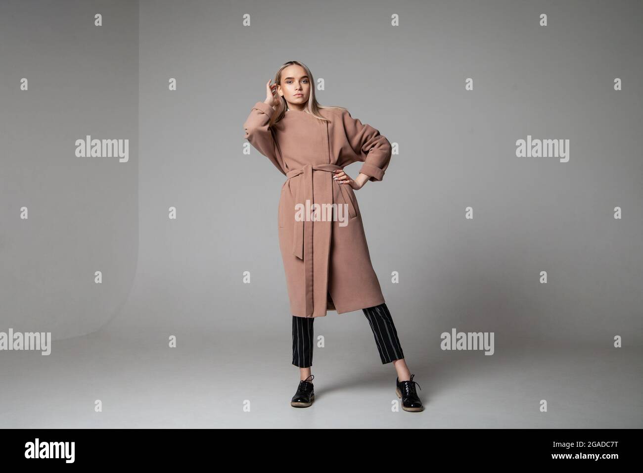 Giovane donna in elegante cappotto che tocca i capelli Foto Stock