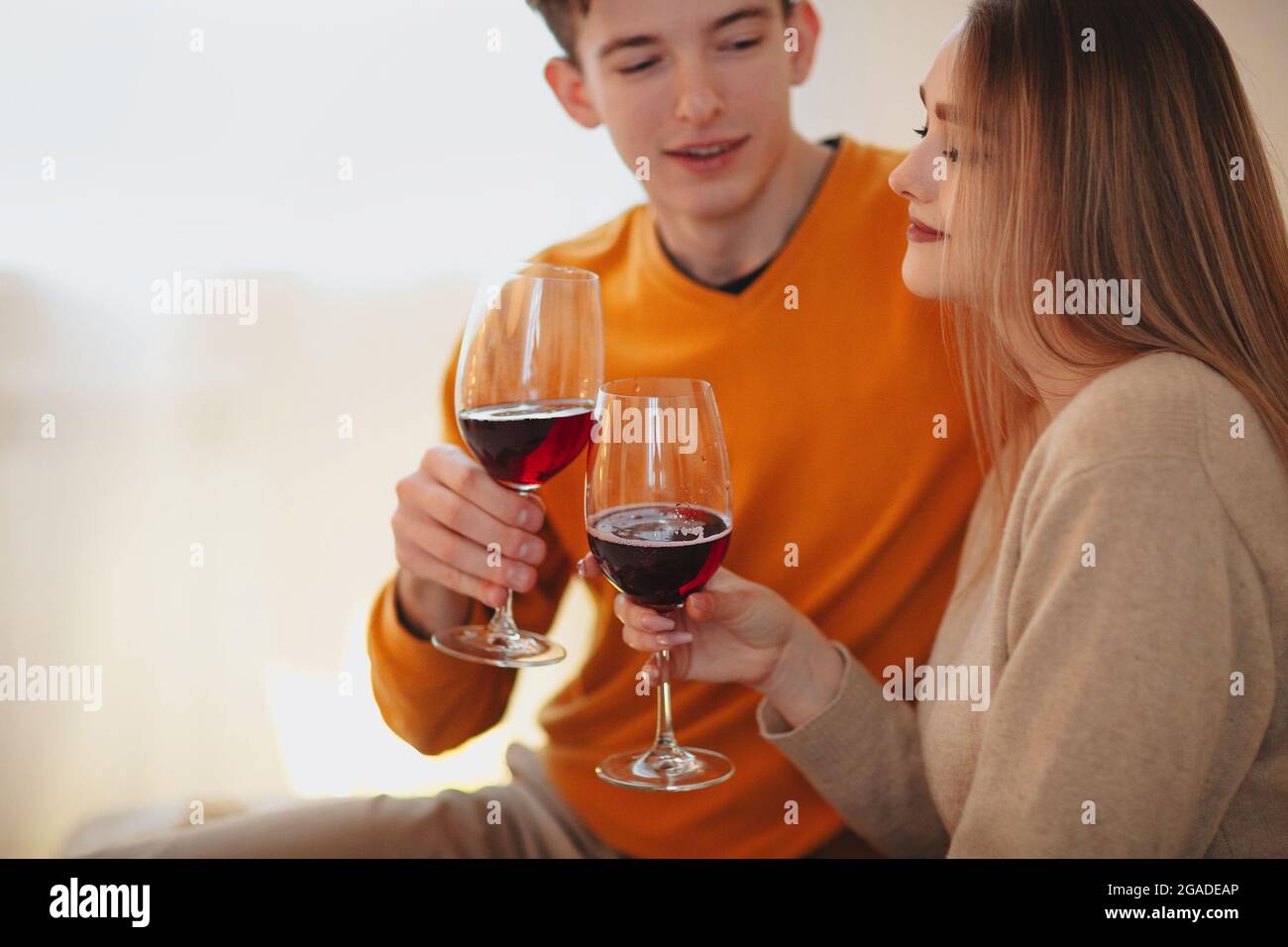 Giovane uomo e donna abbracciano e gustano vino rosso durante la data romantica a casa Foto Stock