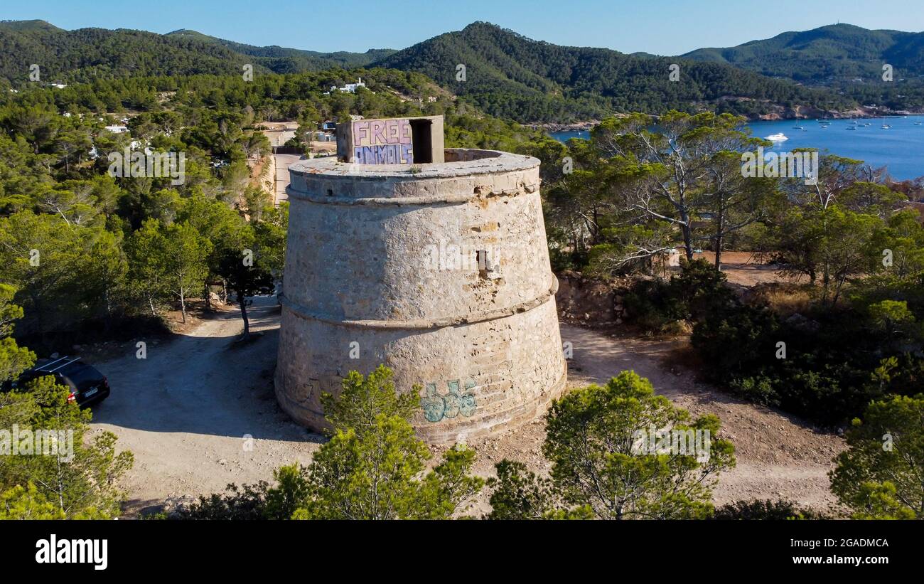 Veduta aerea della Torre rotonda di Portinatx sulla costa settentrionale dell'isola di Ibiza in Spagna - foreste di pini e scogliere rocciose nell'isola delle Baleari Foto Stock