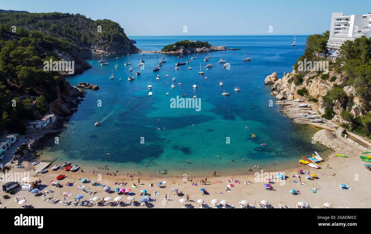 Vista aerea della spiaggia di Port Sant Miquel sulla costa nord dell'isola di Ibiza in Spagna - isolato baia di lato con grandi hotel in collina Foto Stock