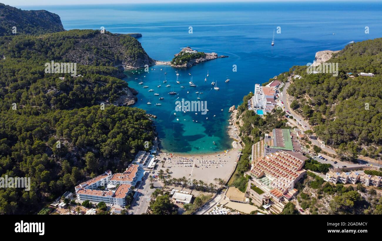 Vista aerea della spiaggia di Port Sant Miquel sulla costa nord dell'isola di Ibiza in Spagna - isolato baia di lato con grandi hotel in collina Foto Stock