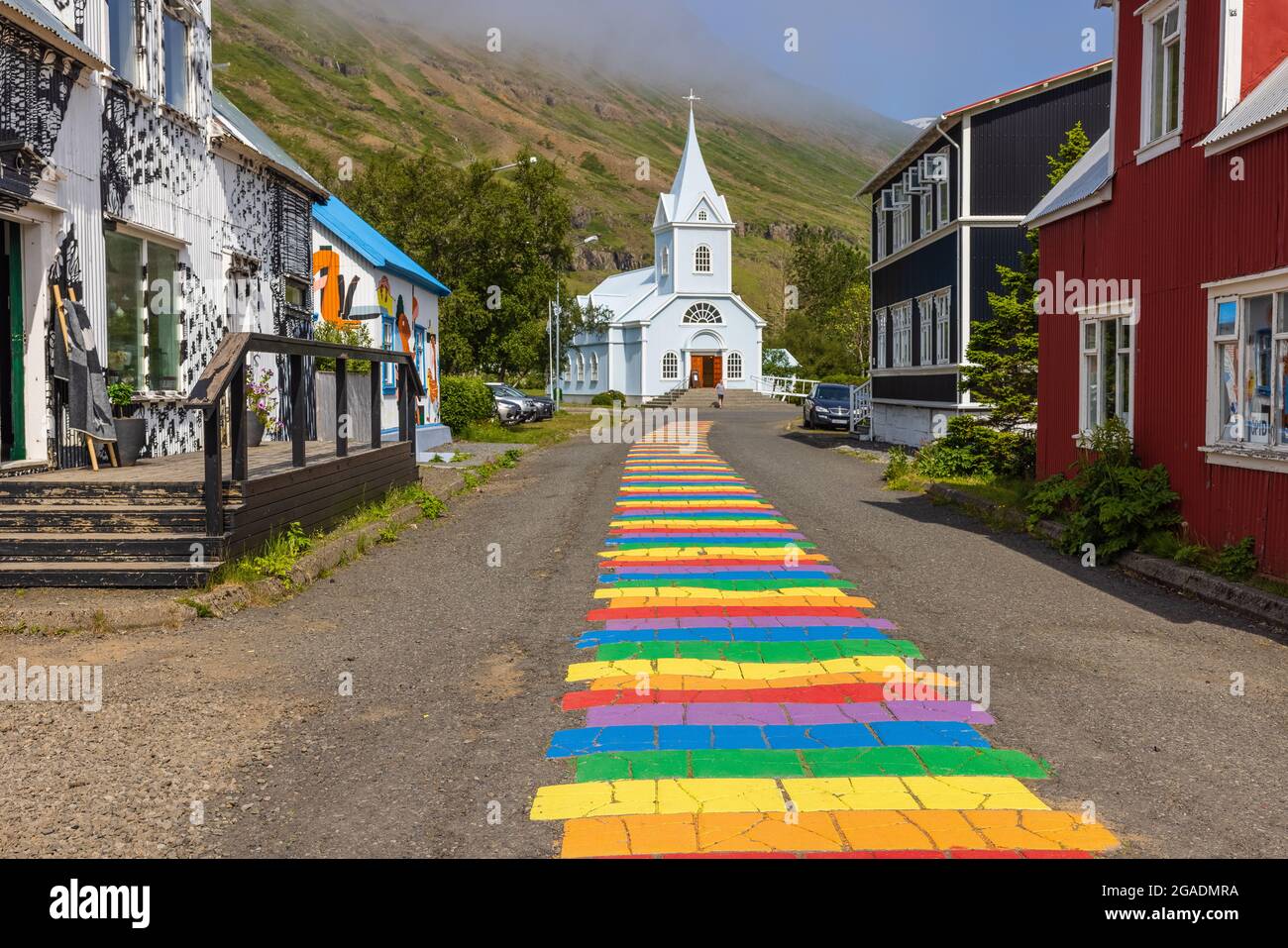 la strada arcobaleno nordurgata alla graziosa chiesa blu in seydisfjordur è stata dipinta nel 2016 Foto Stock