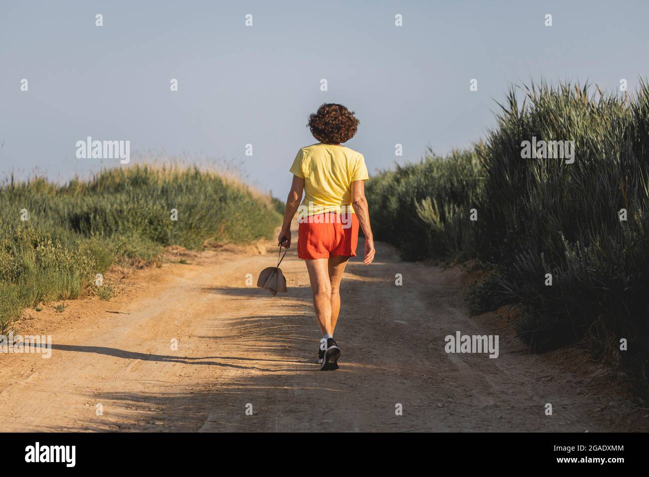 Una donna allegra e vitale, nei suoi anni '70, cammina tranquillamente lungo una pista sterrata nel Parco Naturale Prat de Cabanes, Castellon, Spagna Foto Stock