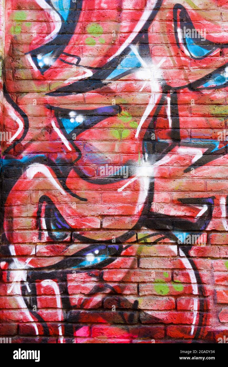 Graffiti astratti di colore rosso, blu e nero su una parete in mattoni. Foto Stock